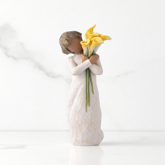 Angel figurine holding yellow flowers on a white background