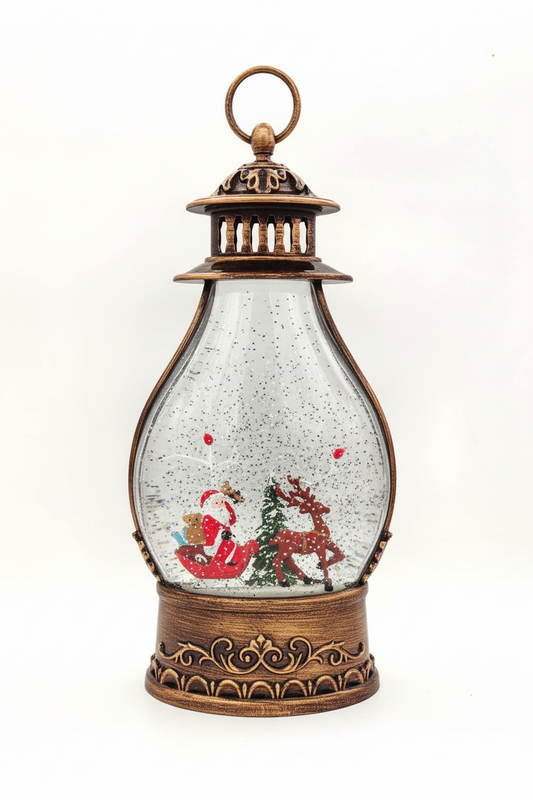 A decorative Christmas snow globe lantern with an ornate bronze-colored metal frame, featuring Santa Claus and a reindeer inside a clear globe filled with white glitter and small red accents, set against a plain white background.