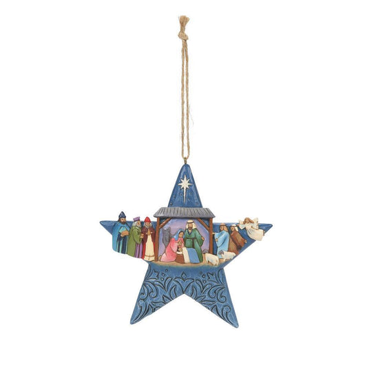 A blue star-shaped hanging ornament featuring an embossed nativity scene with Mary, Joseph, baby Jesus, and three wise men, suspended by a natural jute string against a plain white background.