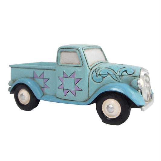 A decorative vintage toy pickup truck in light blue with purple starburst designs on the sides, black wheels, and white-walled tires, shown against a plain white background.