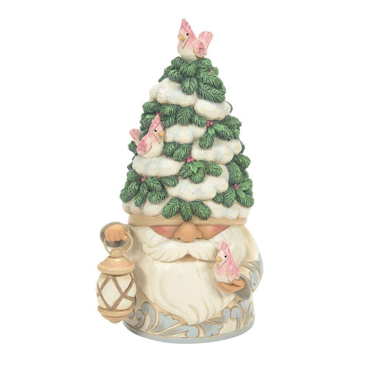 A whimsical gnome figurine with a snowy pine tree on its head, decorated with pink birds, holding a lantern in one hand and a small pink bird in the other, set against a plain white background.