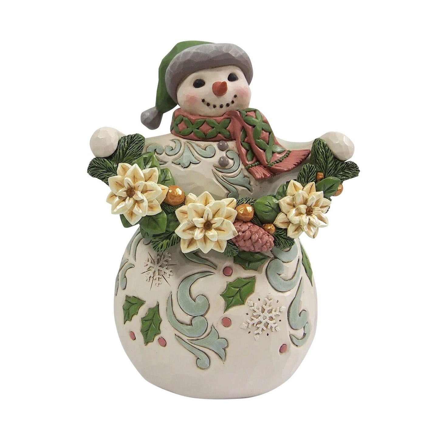 A ceramic Christmas snowman figurine with a green hat and scarf, holding a garland with white flowers, green leaves, pinecones, and snowflake details on its body, set against a plain white background.