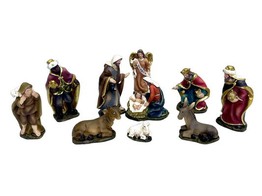 A set of eleven painted nativity figurines arranged on a plain white background, including the Three Wise Men, shepherds, angels, the Holy Family, and animals.