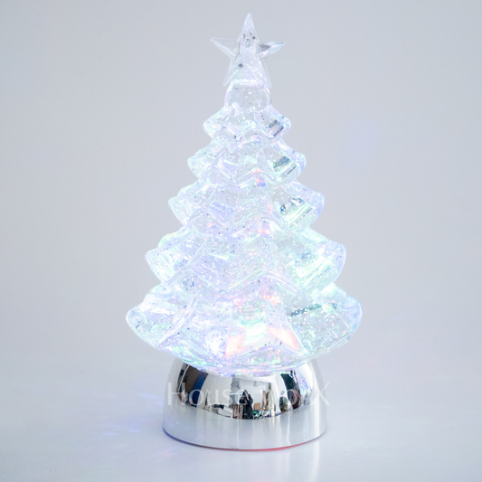 Decorative Christmas tree with LED lights on a reflective base against a light gray background snow globe