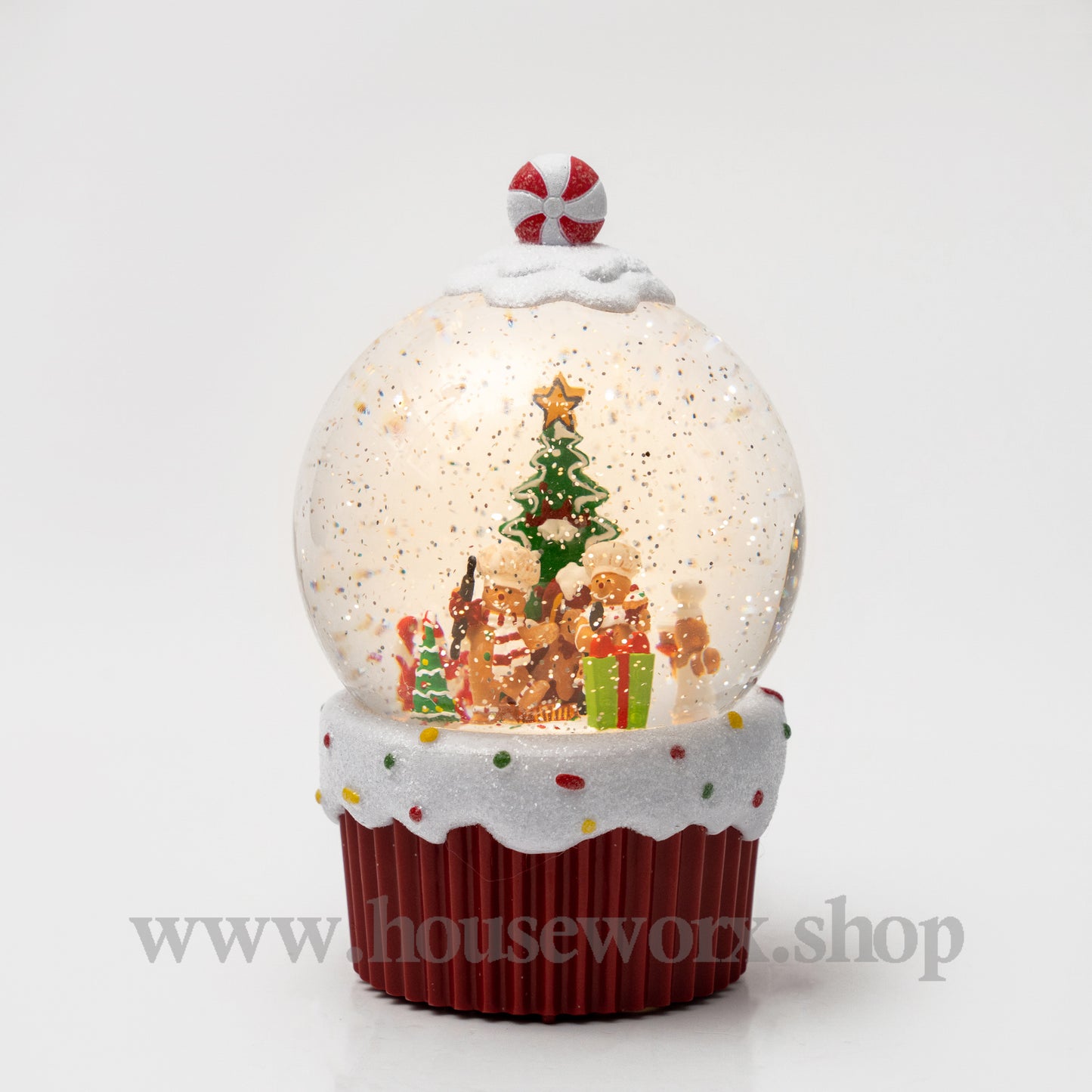 Christmas-themed snow globe with gingerbread people and a tree on a white background