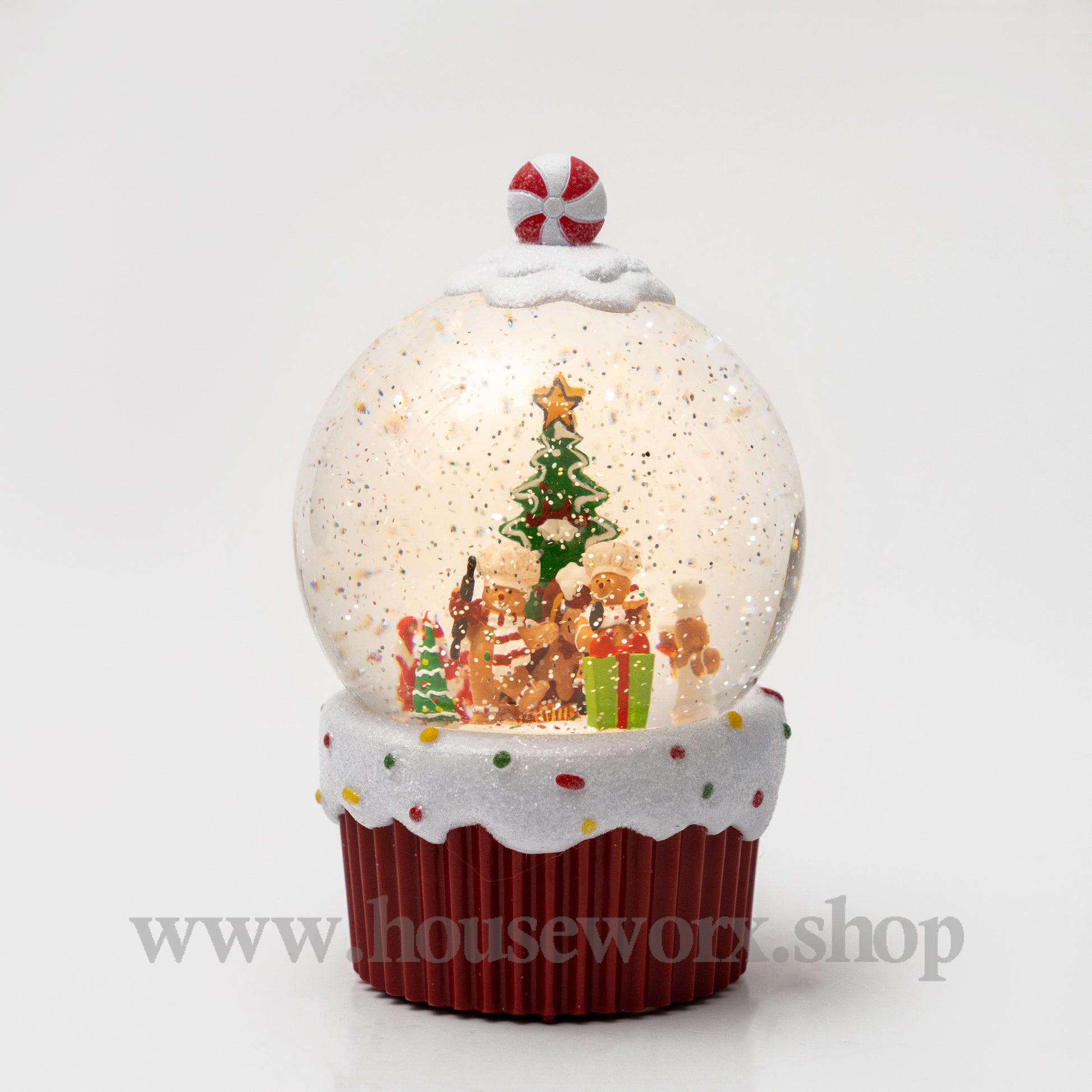 Christmas-themed snow globe with gingerbread people and a tree on a white background