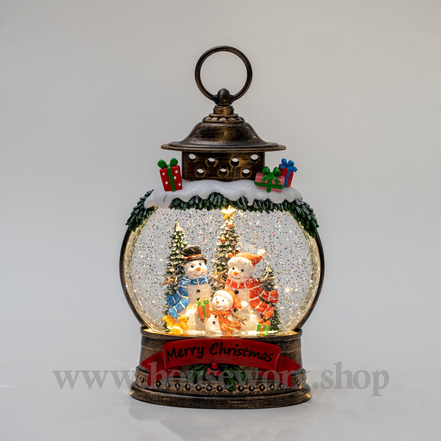Decorative snow globe with Christmas scene inside a lantern on a gray background