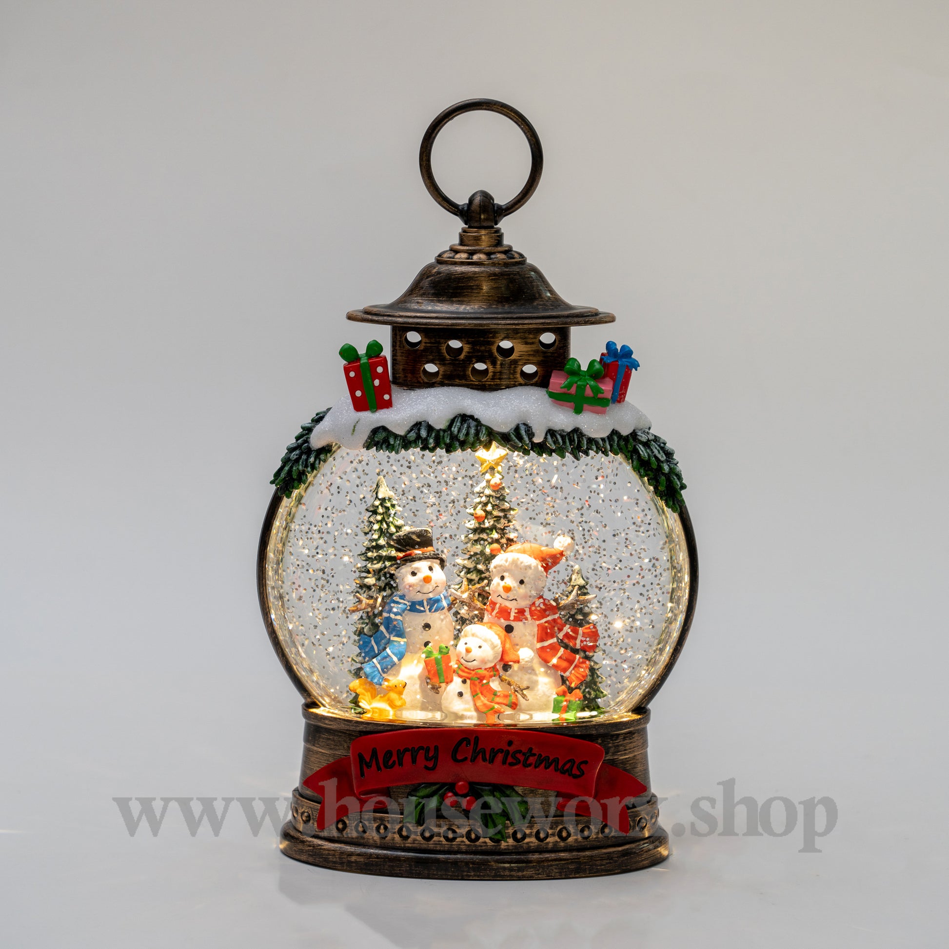 Decorative snow globe with Christmas scene inside a lantern on a gray background