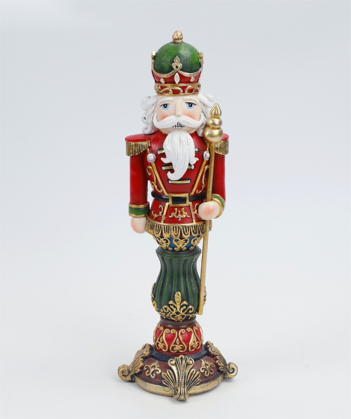 A detailed, hand-painted nutcracker figurine standing on an ornate base. The nutcracker is dressed in a red and green military uniform with gold trim, a white beard, and a green and gold crown, holding a gold staff.