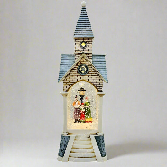 Decorative clock tower with a lit scene inside on a white background