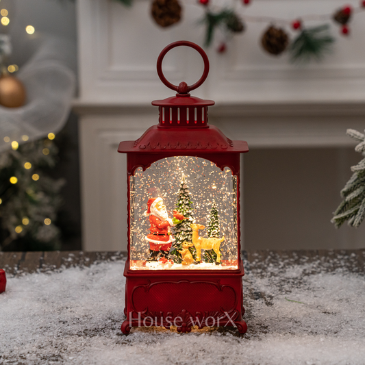 Red lantern with a Christmas scene featuring Santa Claus and a reindeer, placed on a snowy surface.