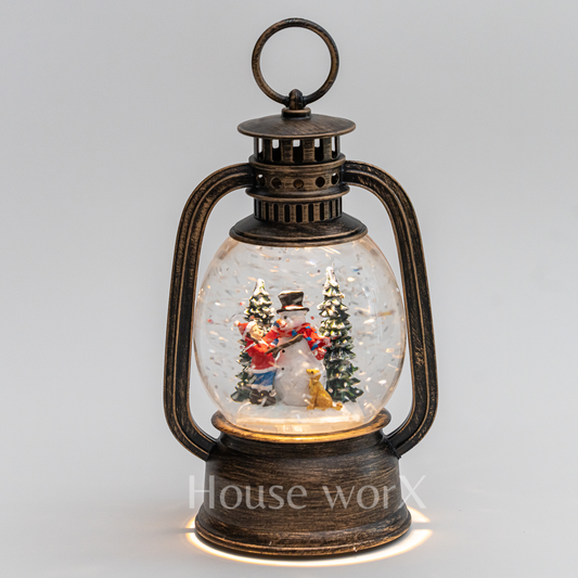 Decorative lantern with a snow globe featuring Christmas scenes on a light gray background.