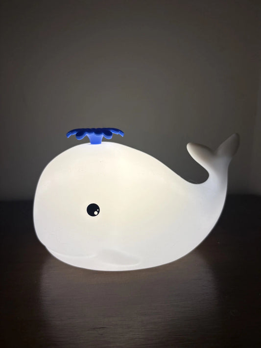 Whale-shaped night light on a dark surface with a dark background