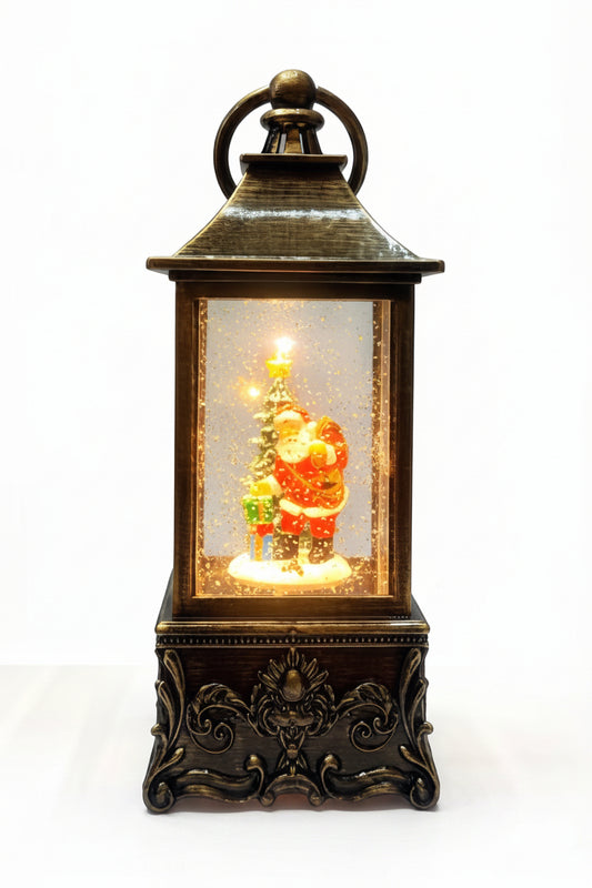 A decorative lantern-shaped Christmas ornament with a dark bronze metal frame, featuring a Santa Claus and tree scene illuminated from within, set against a plain white background.