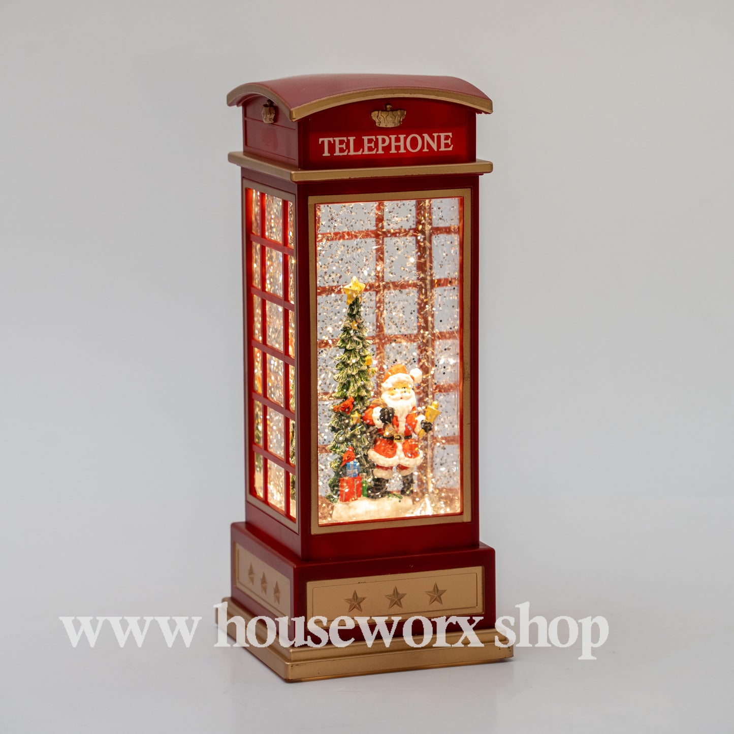 Decorative Christmas scene inside a telephone booth with Santa Claus and a tree, on a gray background. Christmas snow globe