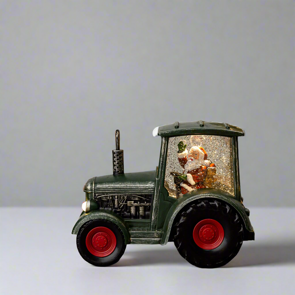 Decorative tractor with a snow globe inside on a light gray background