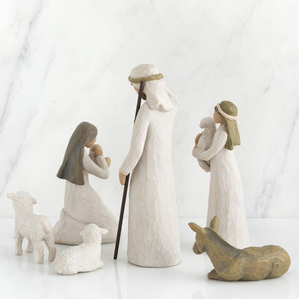 A set of six Willow Tree figurines depicting the Holy Family, wise men, and animals, displayed on a white surface against a white marble background.