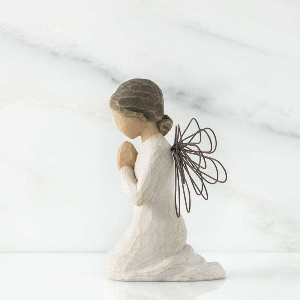 Angel figurine with a white robe and brown hair on a marble background