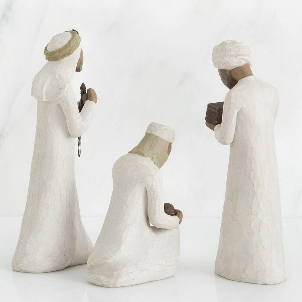 Three stone sculptures of people in traditional attire on a white background
