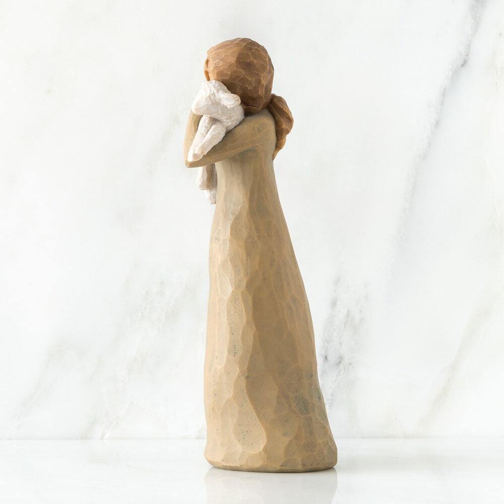 Wooden figurine of a woman holding a baby against a white background