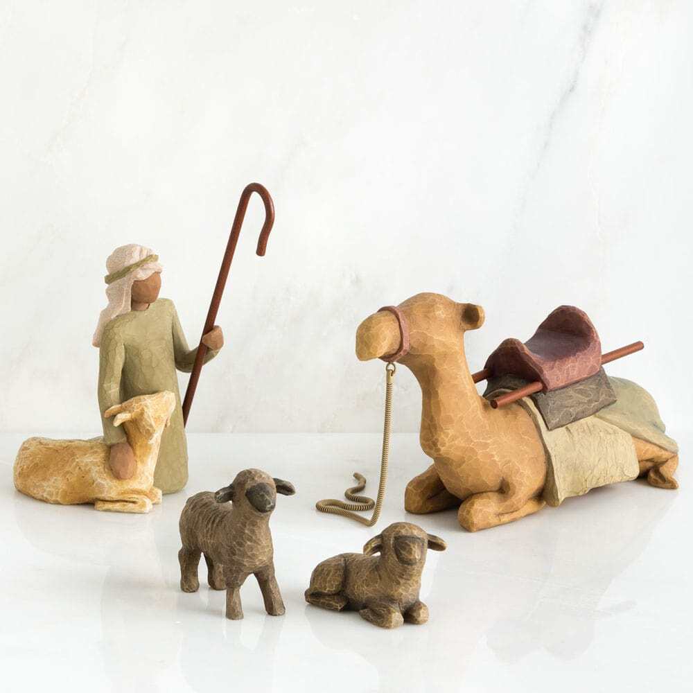 Wooden nativity scene figures including a shepherd, two sheep, and a camel on a white background