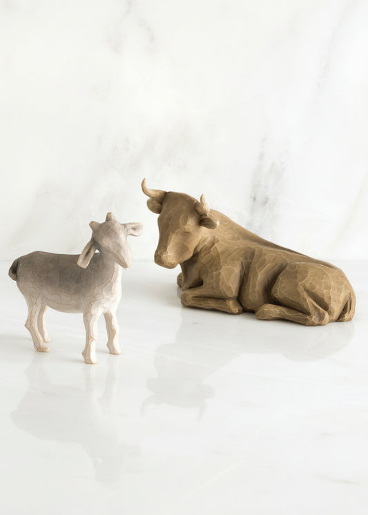 Wooden figurines of a bull and a goat on a white background