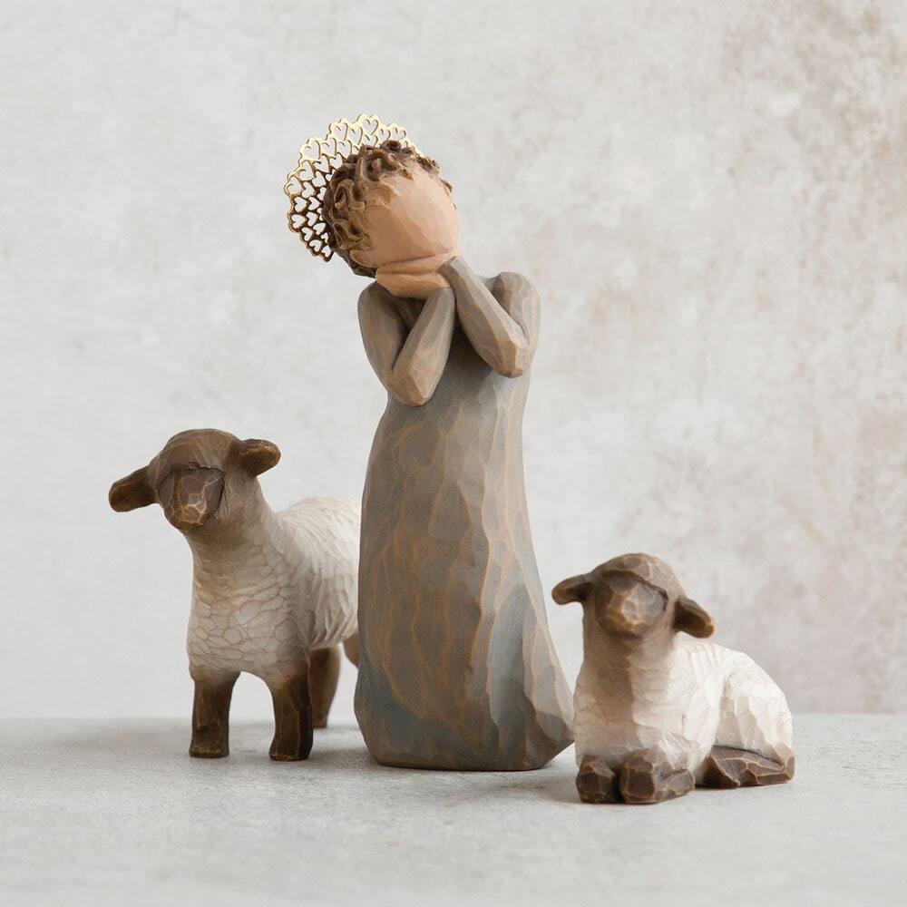 Three ceramic figures of a woman and two sheep on a light background