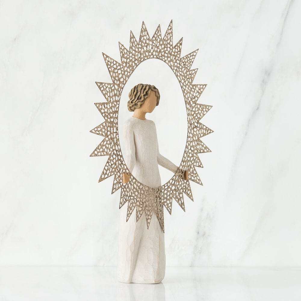 A decorative figurine of a woman in a long white dress standing in front of a large, ornate sunburst mirror with a gold-toned frame, set against a light marble background.