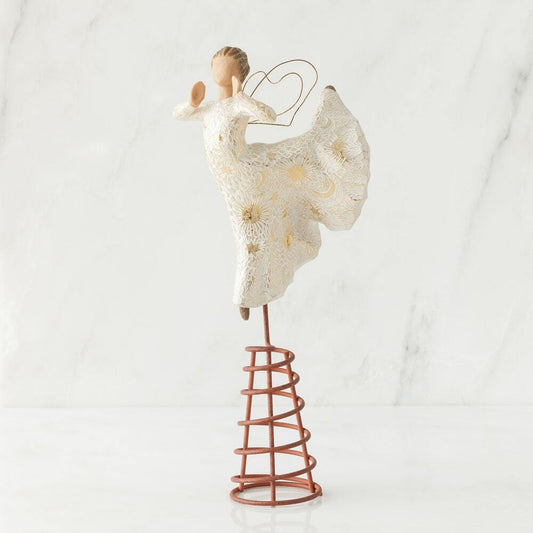A decorative angel figurine with a white lace-like dress and gold floral accents, mounted on a spiral copper-toned stand against a light marble background.