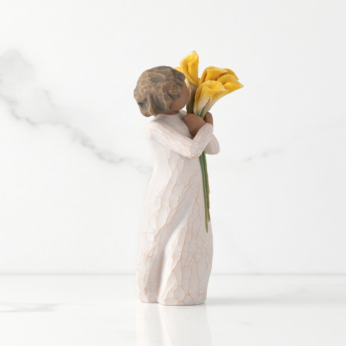 Figurine of a child holding yellow flowers against a white background