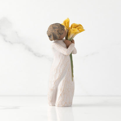 Figurine of a child holding yellow flowers against a white background