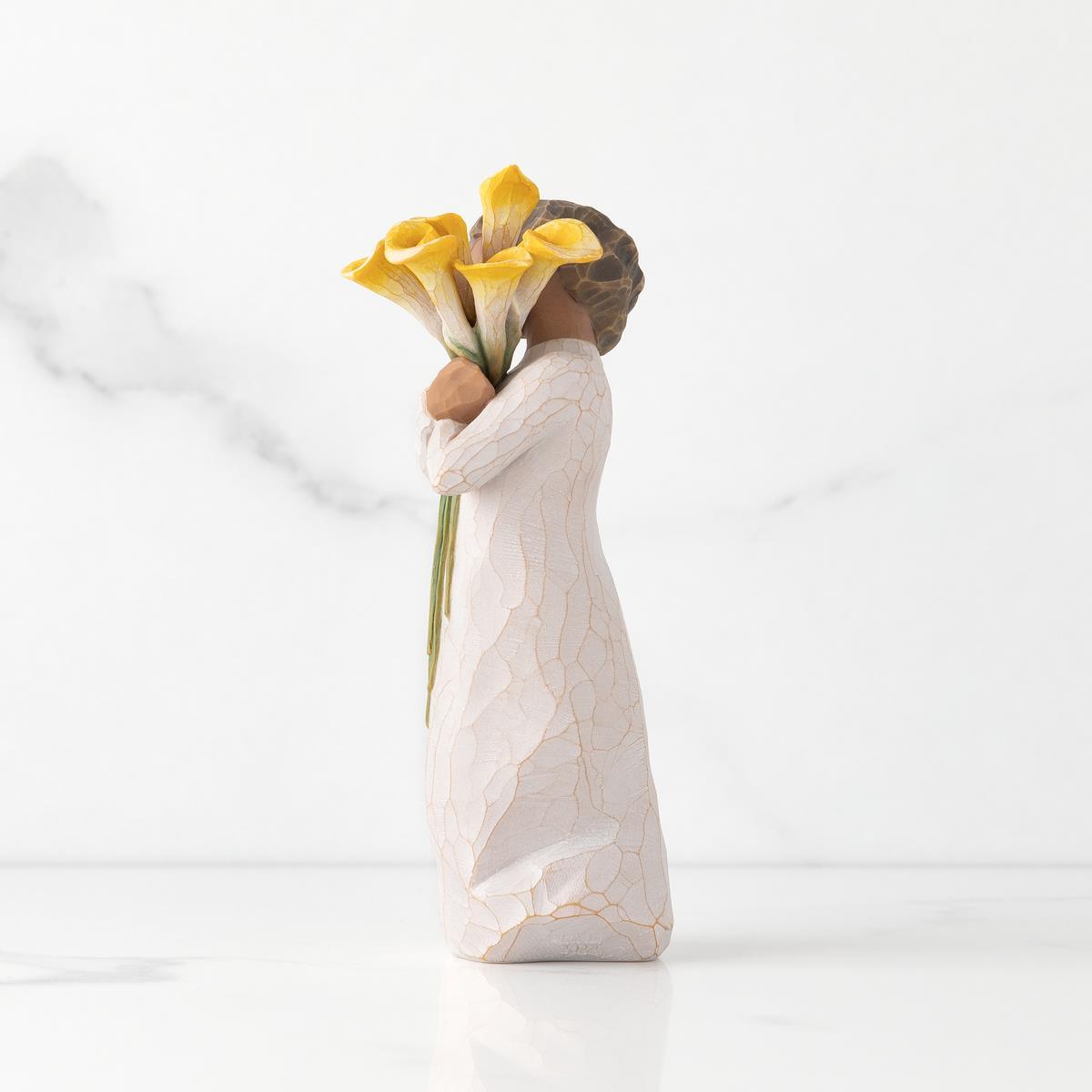 Statue of a person holding yellow flowers against a white background