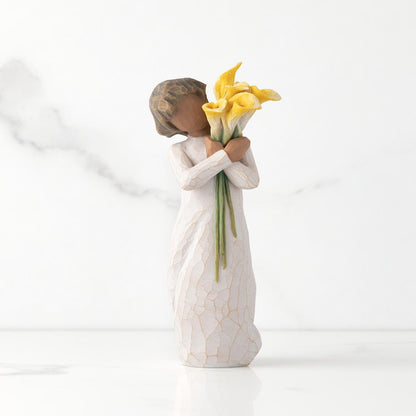 Angel figurine holding yellow flowers on a white background