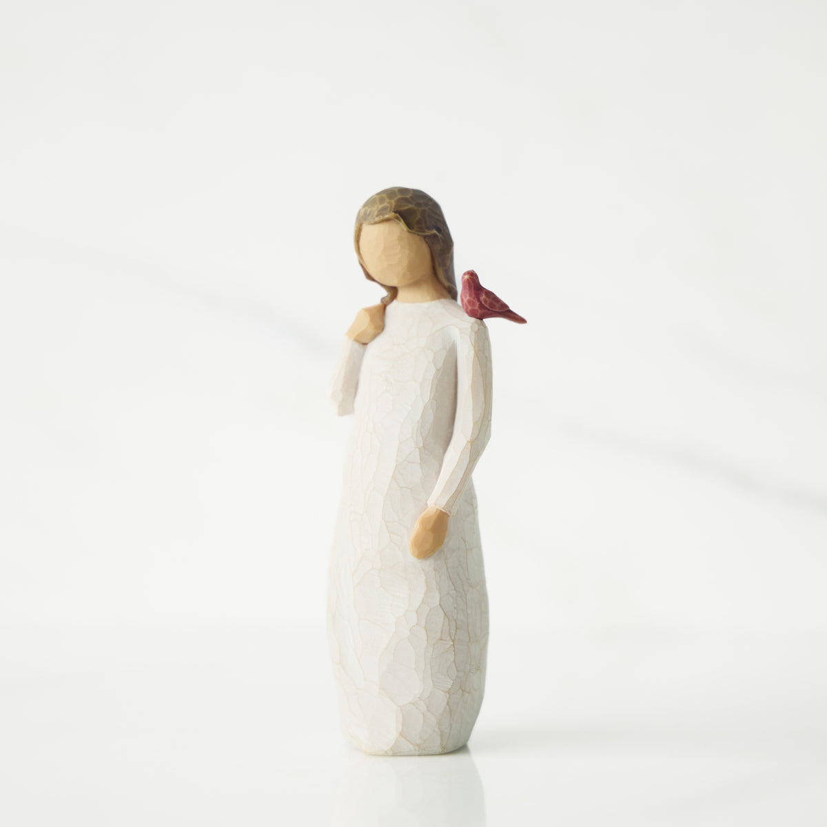 White figurine of a girl with a bird on her shoulder against a white background