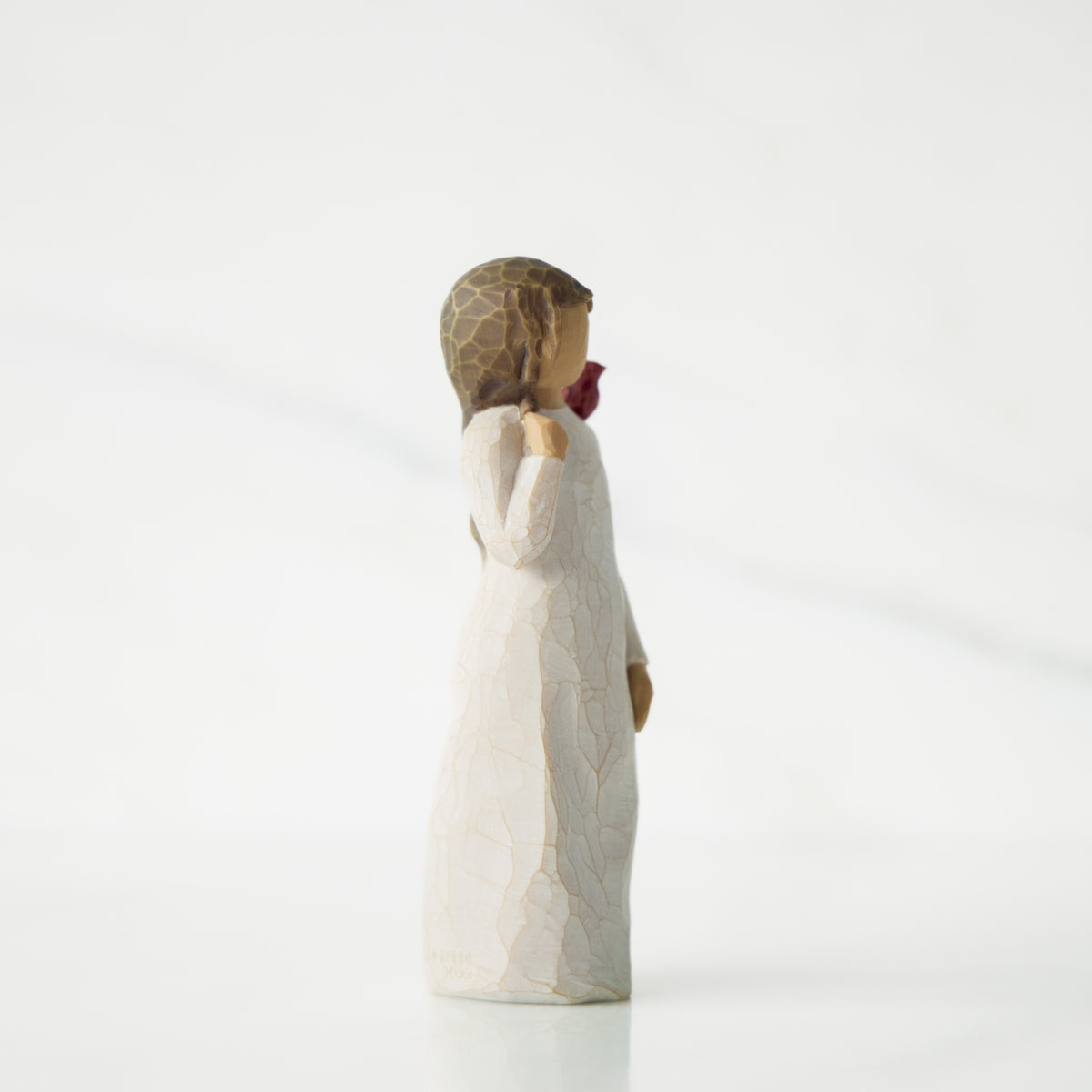 Statue of a woman in a long dress holding a bouquet on a white background
