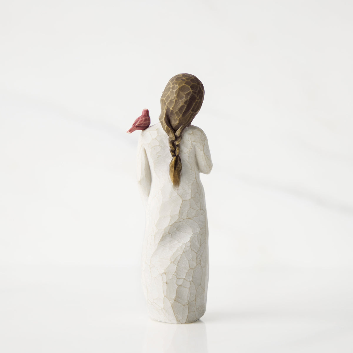White ceramic figurine of a woman with braided hair on a white background