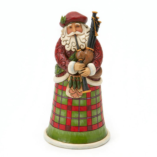 A Santa Claus figurine playing a bagpipe, dressed in a red jacket and green tartan skirt, on a plain white background.