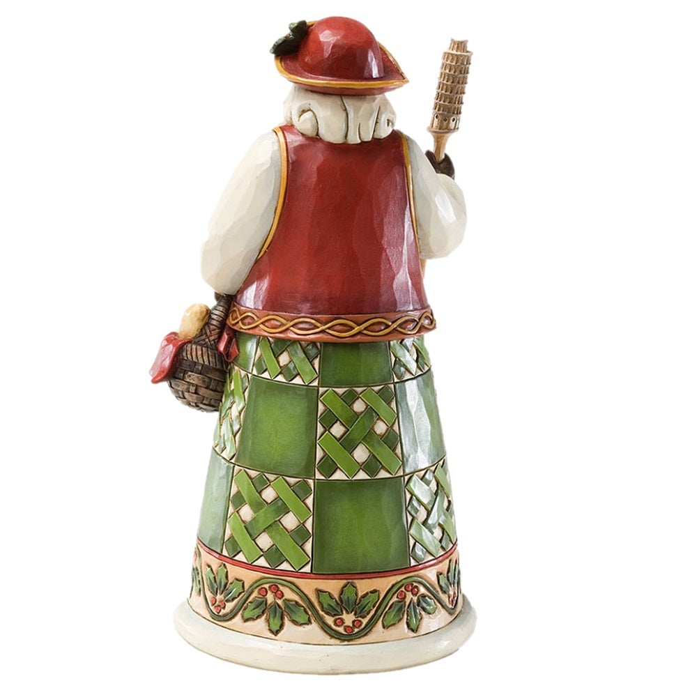A ceramic figurine of a traditional Irish man with a white beard, wearing a red vest, green patterned skirt, and red hat, holding a basket and staff, shown from the back against a white background.