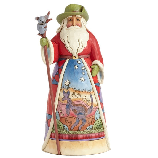 A Jim Shore Santa figurine wearing a green hat and a red robe with a detailed kangaroo and starry sky design on the front, holding a staff with a small koala on it, set against a plain white background.