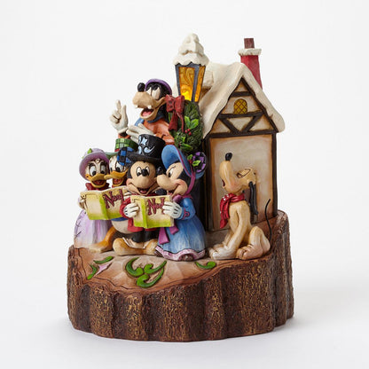 A Disney holiday figurine set featuring Mickey, Minnie, Goofy, Pluto, and Daisy in a snowy cottage scene on a log base, photographed against a clean white background.