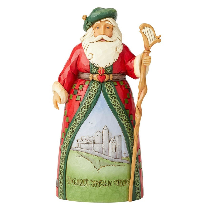 A Jim Shore figurine of Saint Patrick holding a harp and staff, dressed in a red robe with green borders and a green hat, standing on a white background.