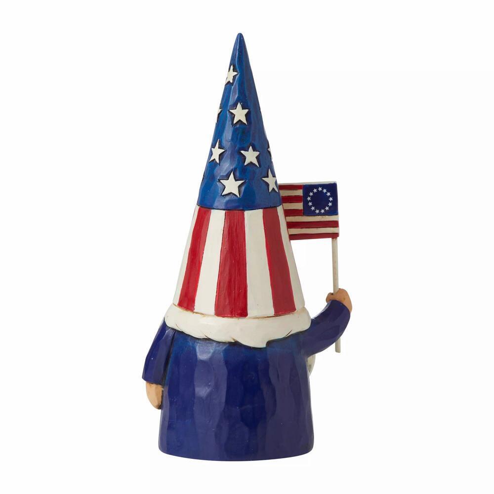 A patriotic garden gnome figurine wearing a tall pointed hat with an American flag pattern, holding a small Betsy Ross style flag, set against a plain white background.