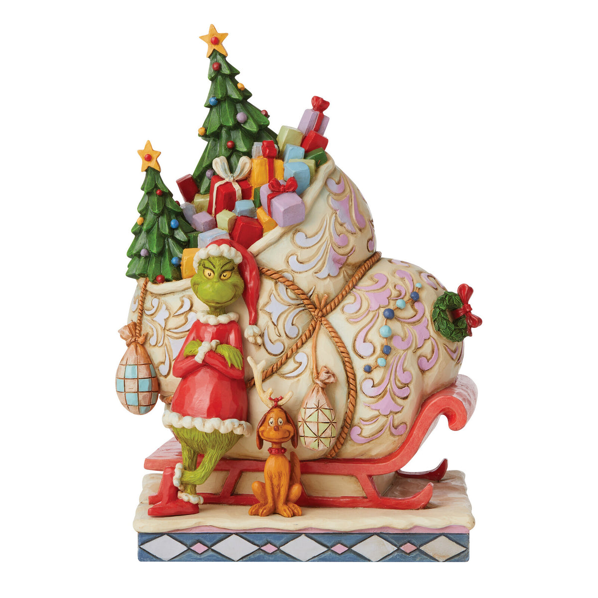 A decorative figurine of the Grinch in a red Santa outfit standing beside a sleigh loaded with Christmas trees, wrapped gifts, and ornaments, on a white studio background.