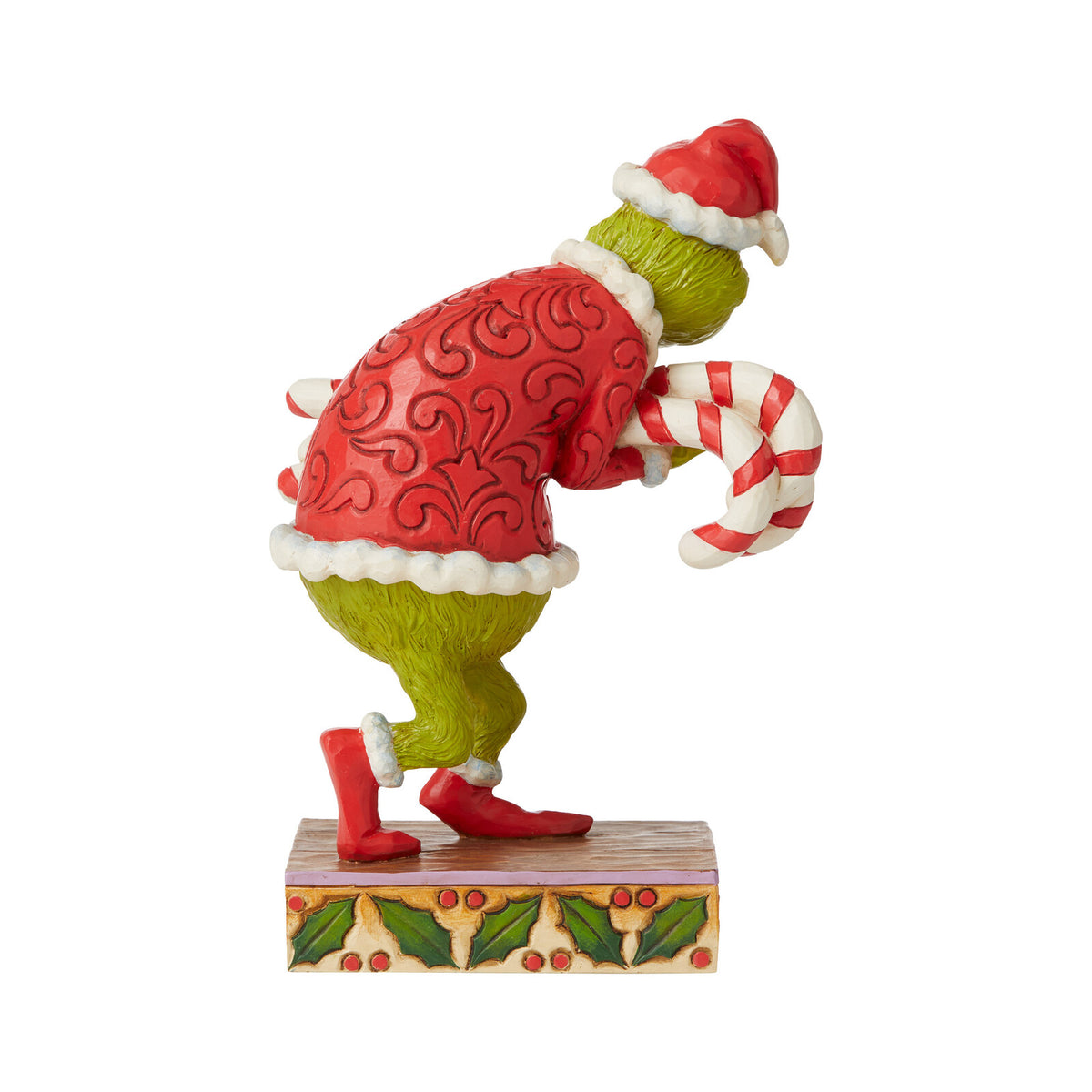 Figurine of a character in a red outfit with green pants, holding a candy cane on a white background.