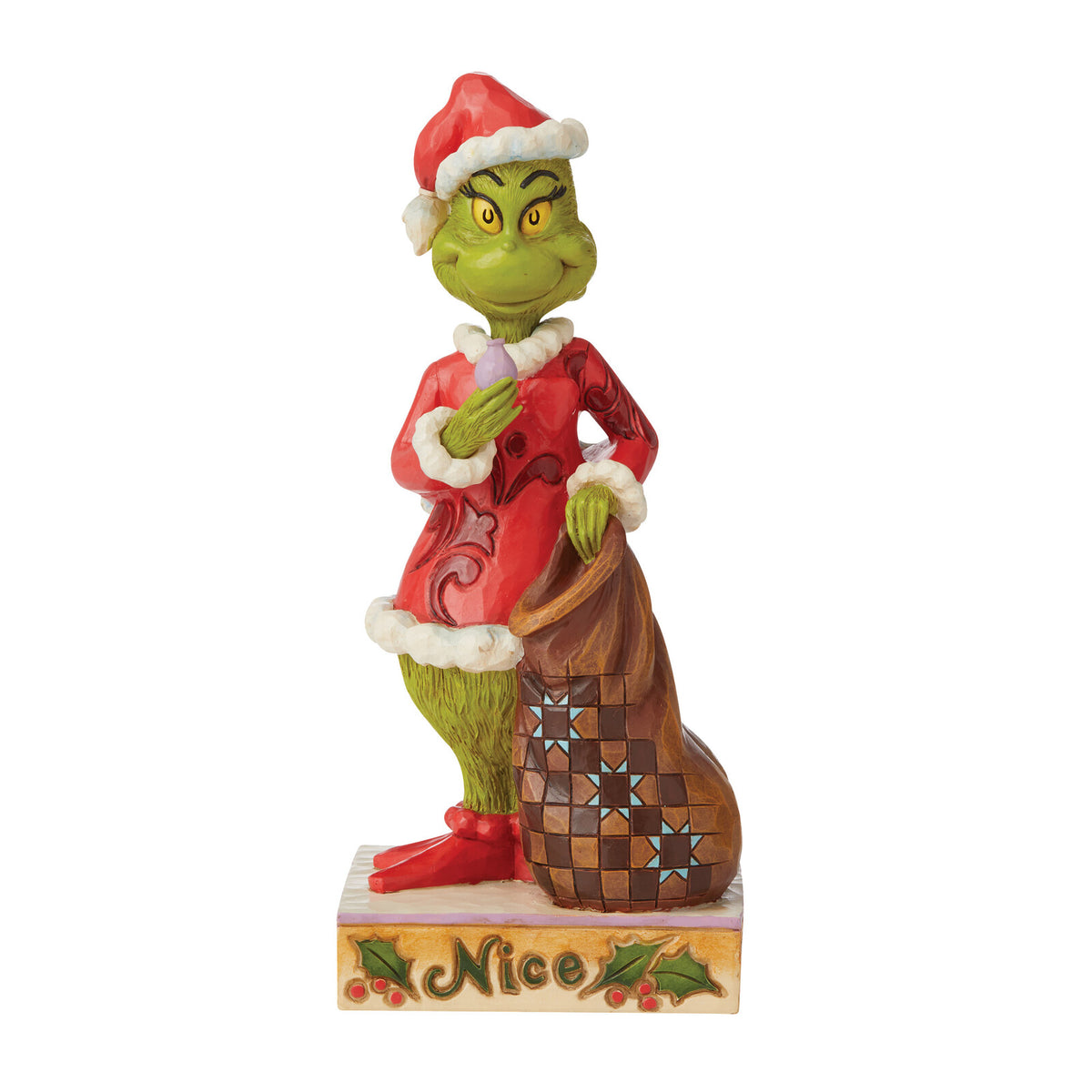A Grinch figurine wearing a red Santa suit and Santa hat, holding a brown patterned sack, standing on a base that says 'Nice' with holly and berries, on a white background.