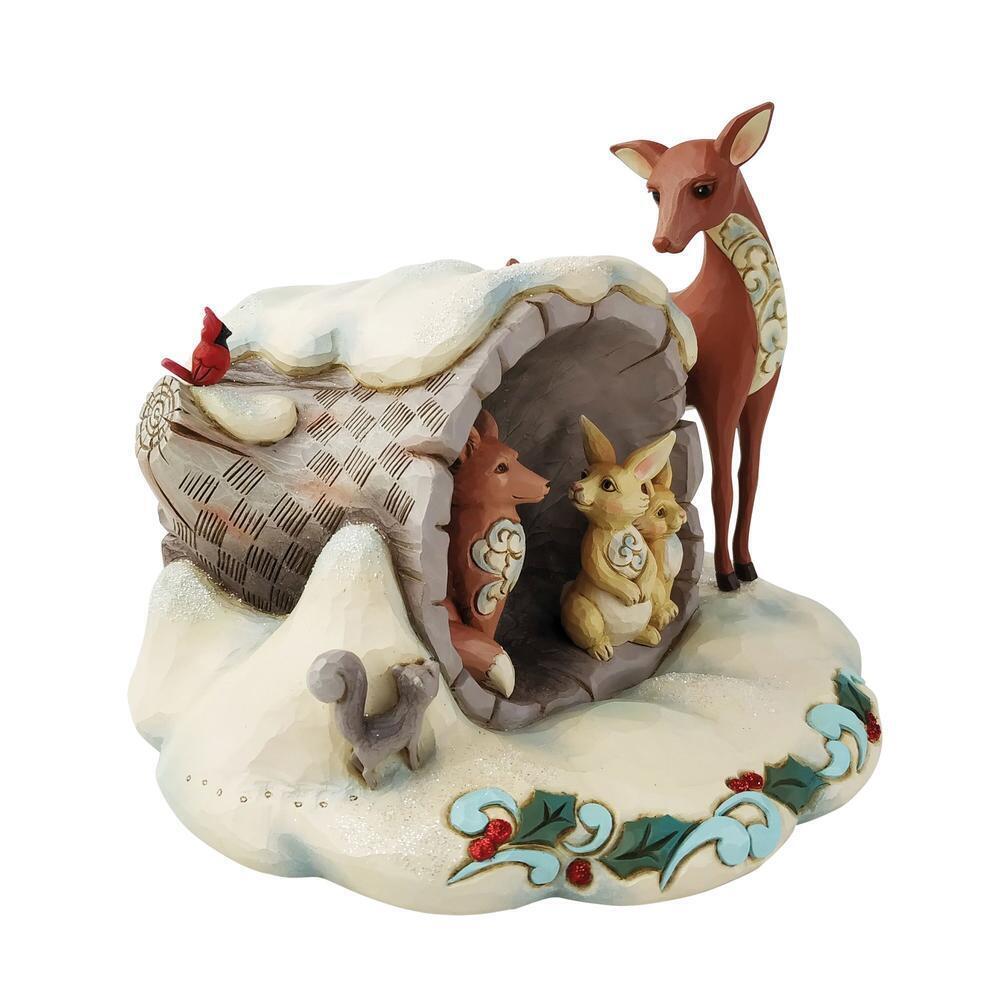 A decorative winter woodland figurine featuring a small treehouse with animals, including a deer standing outside, a bird on top, a squirrel at the base, and a small rabbit inside. The scene is styled with snow, greenery, and floral accents on a plain white background.