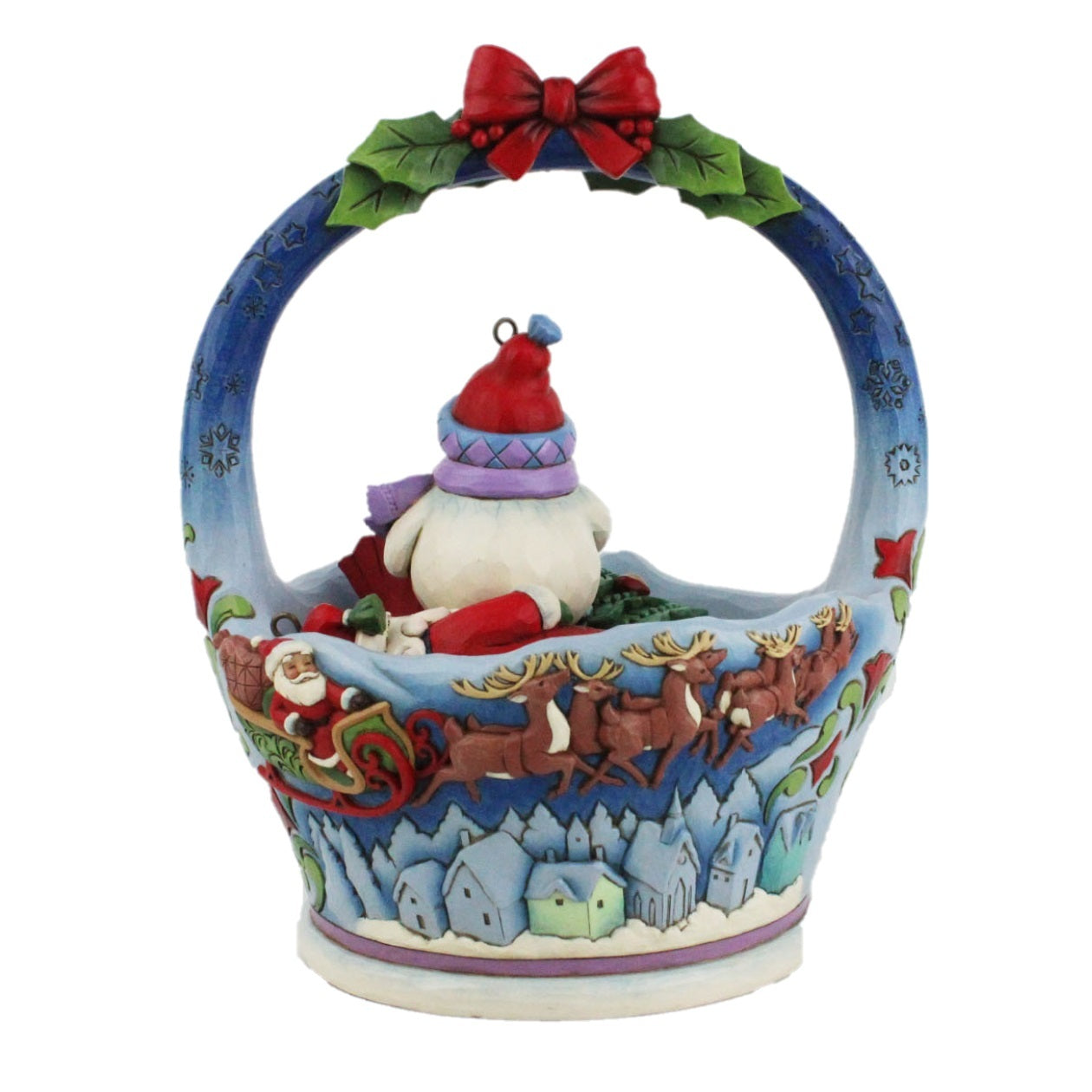 A decorative Christmas basket ornament featuring Santa Claus in a sleigh with reindeer, a snowman figure, and a red bow with green holly leaves on a blue-handled basket, shown on a plain white background.
