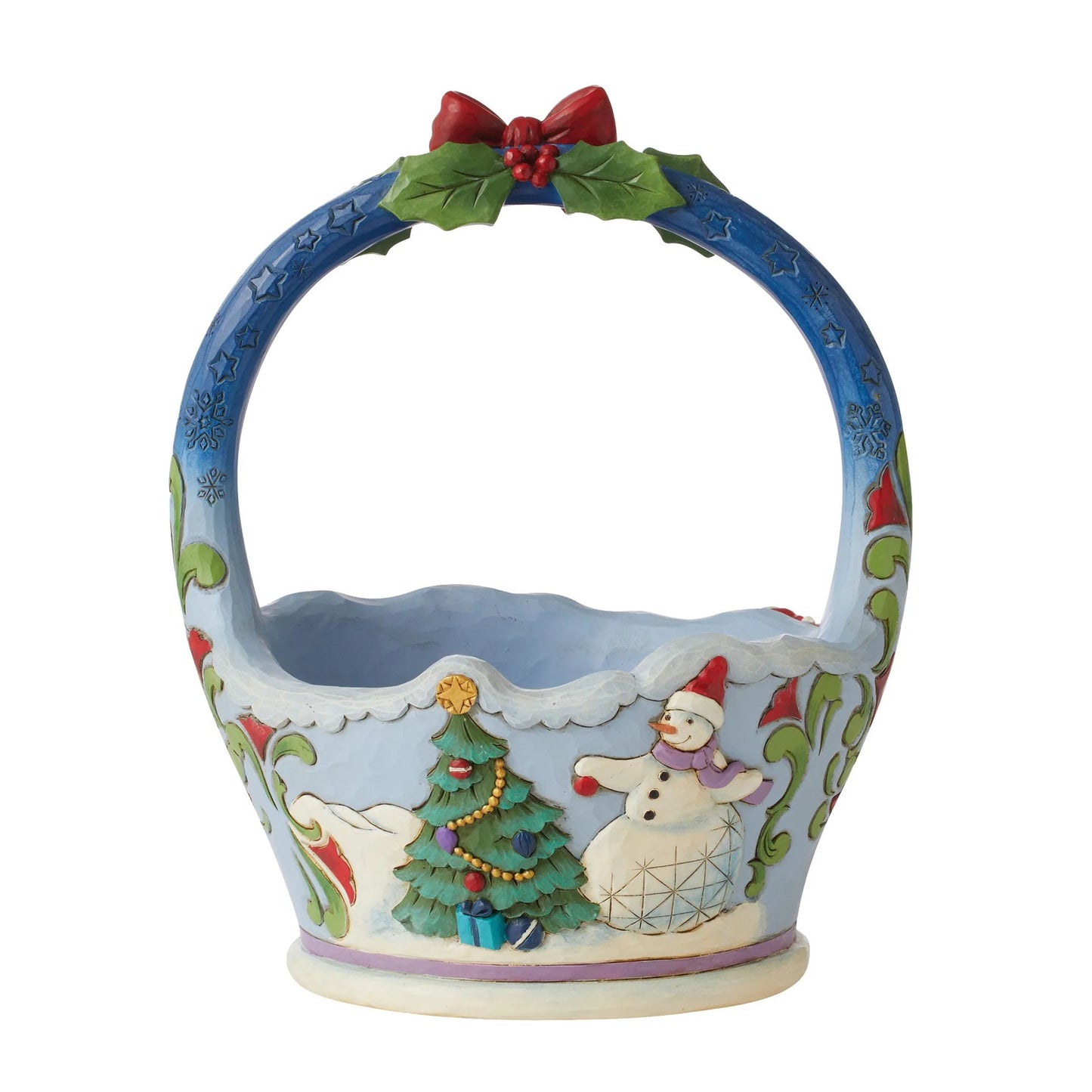 A ceramic Christmas basket with a blue handle decorated with a red bow and green holly leaves, featuring a winter scene with a snowman, Christmas tree, and snow on the basket body.