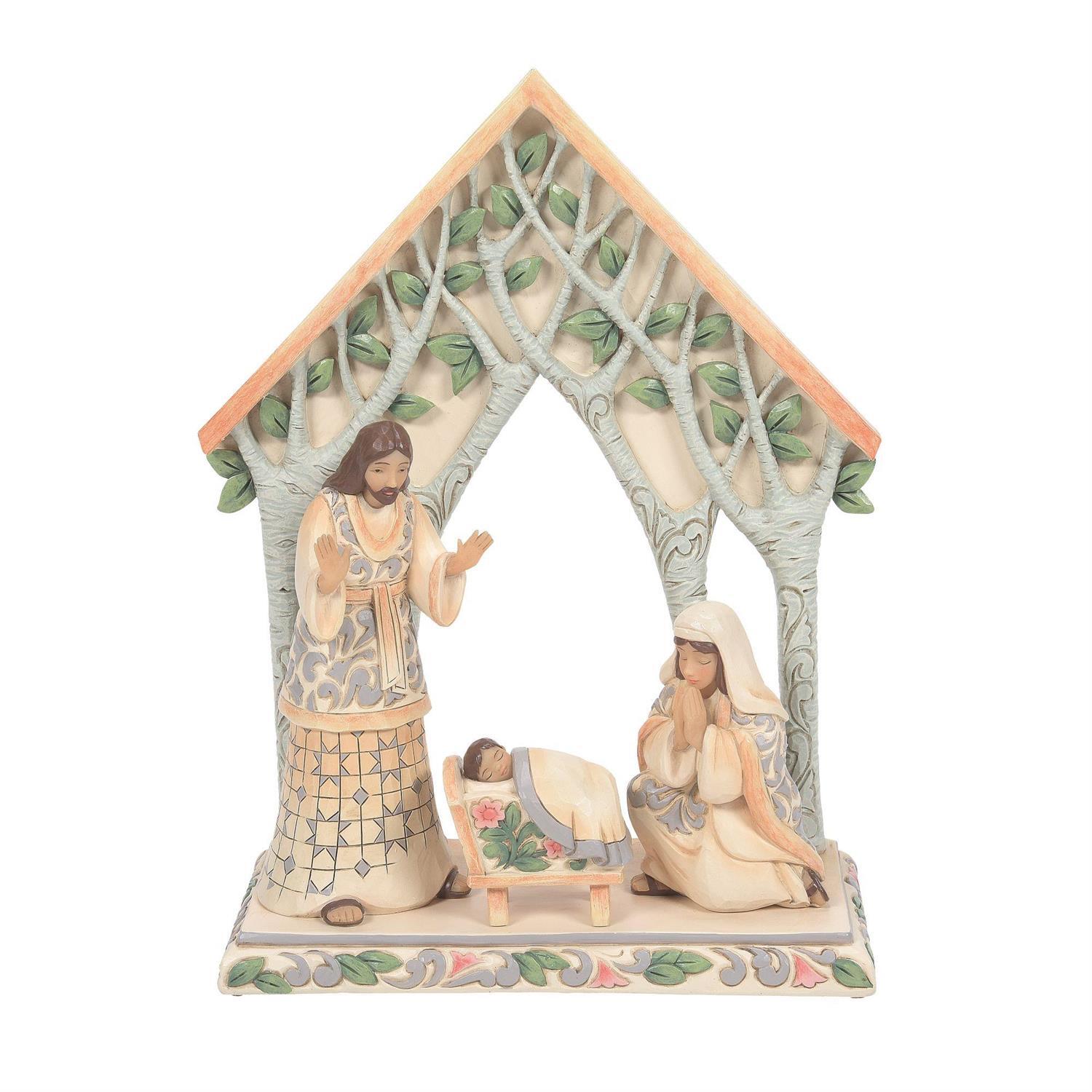 A nativity scene figurine under a house-shaped tree canopy, featuring Mary, Joseph, and baby Jesus on a decorative base against a white background.