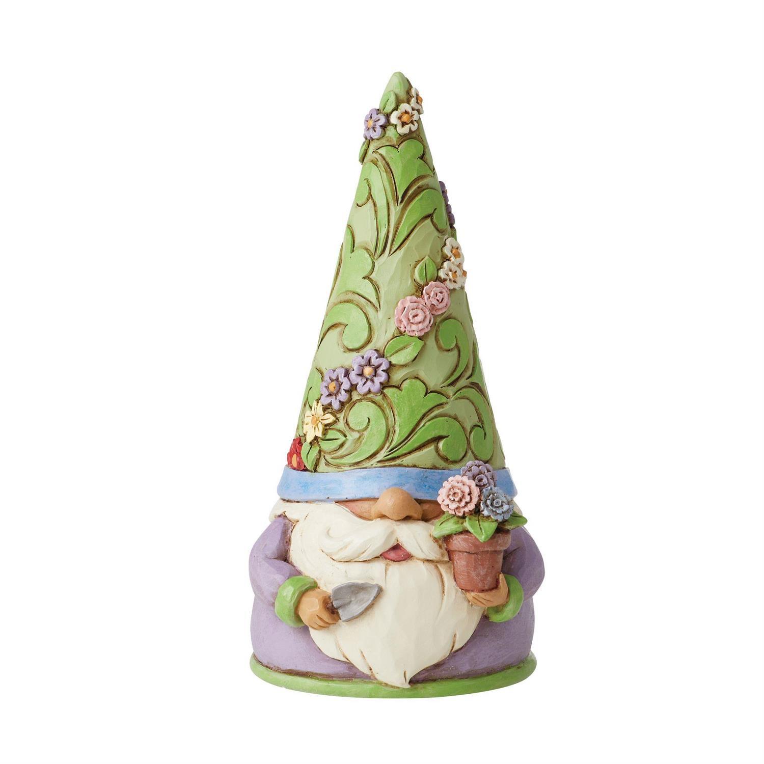 A decorative garden gnome figurine with a tall green hat decorated with floral and vine patterns, a blue band, a white beard, and a lavender-purple body, holding a small flower pot and gardening tools.